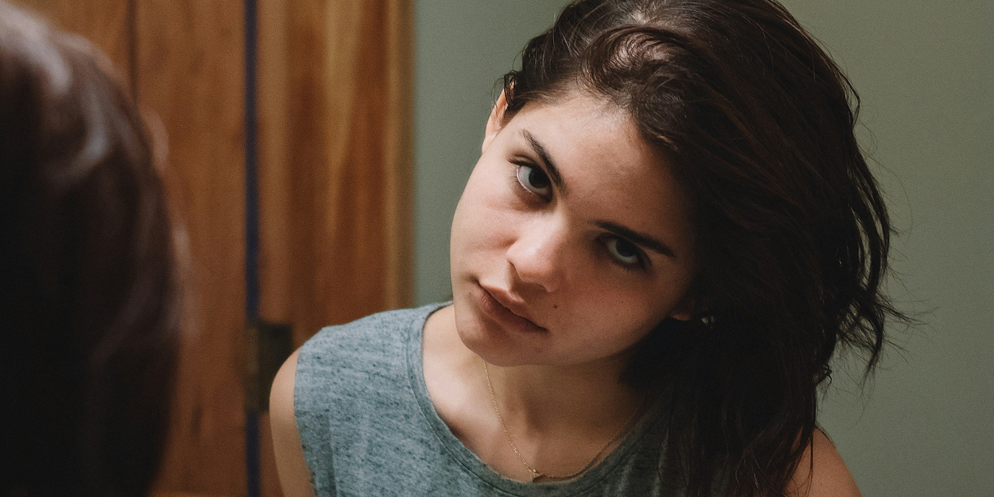 Femme observant sa raie élargie dans un miroir, signe d'alopécie androgénétique liée au SOPK