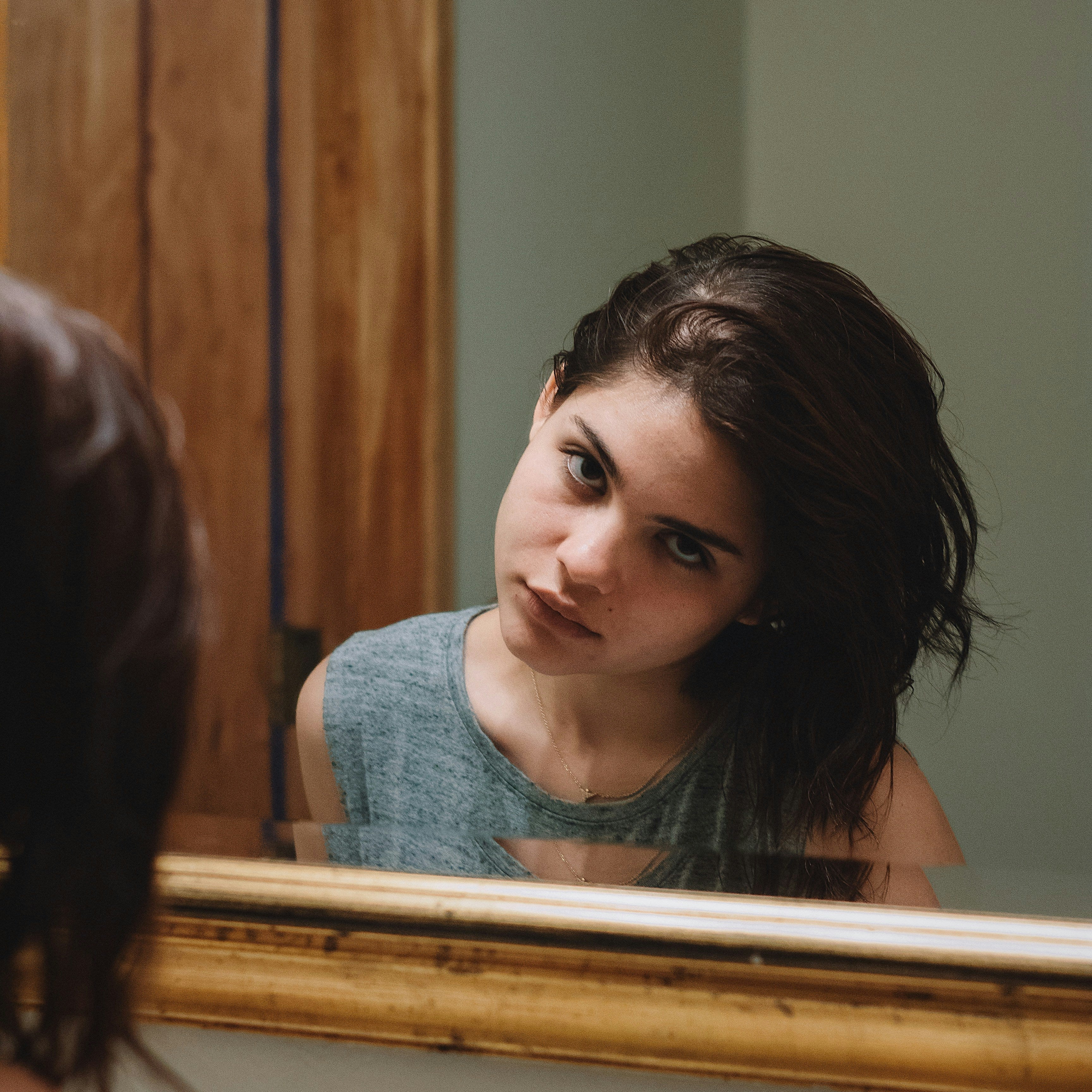 Femme observant sa raie élargie dans un miroir, signe d'alopécie androgénétique liée au SOPK