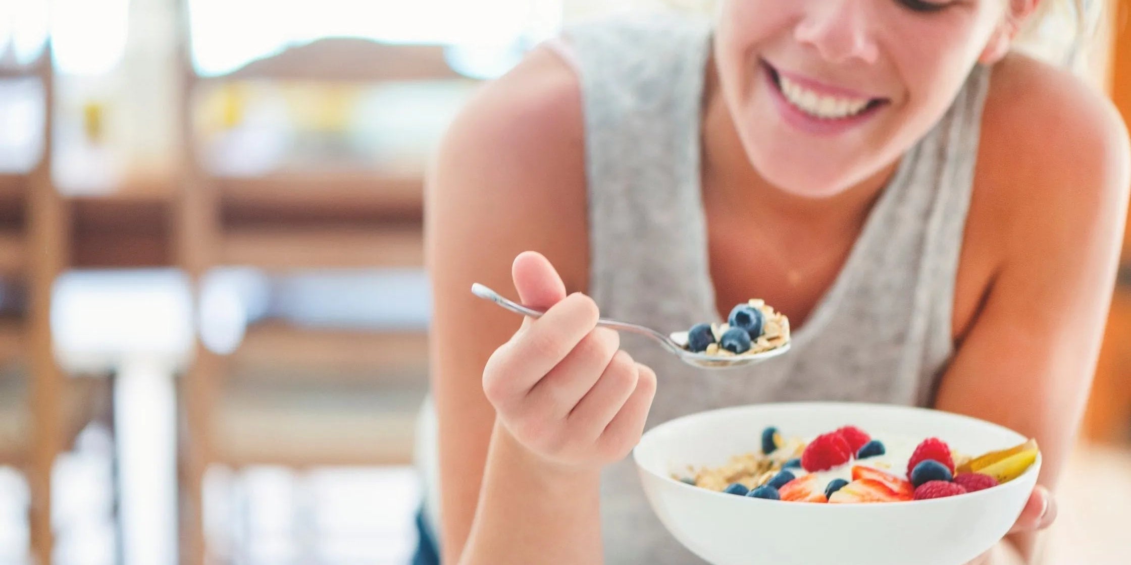 Femme atteinte de SOPK mesurant son tour de taille dans une cuisine lumineuse, assiette de légumes et protéines au premier plan